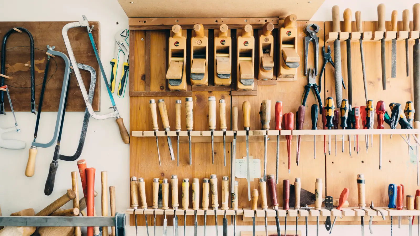 Mur d'atelier garni d'outils rangés : scies, tournevis et limes