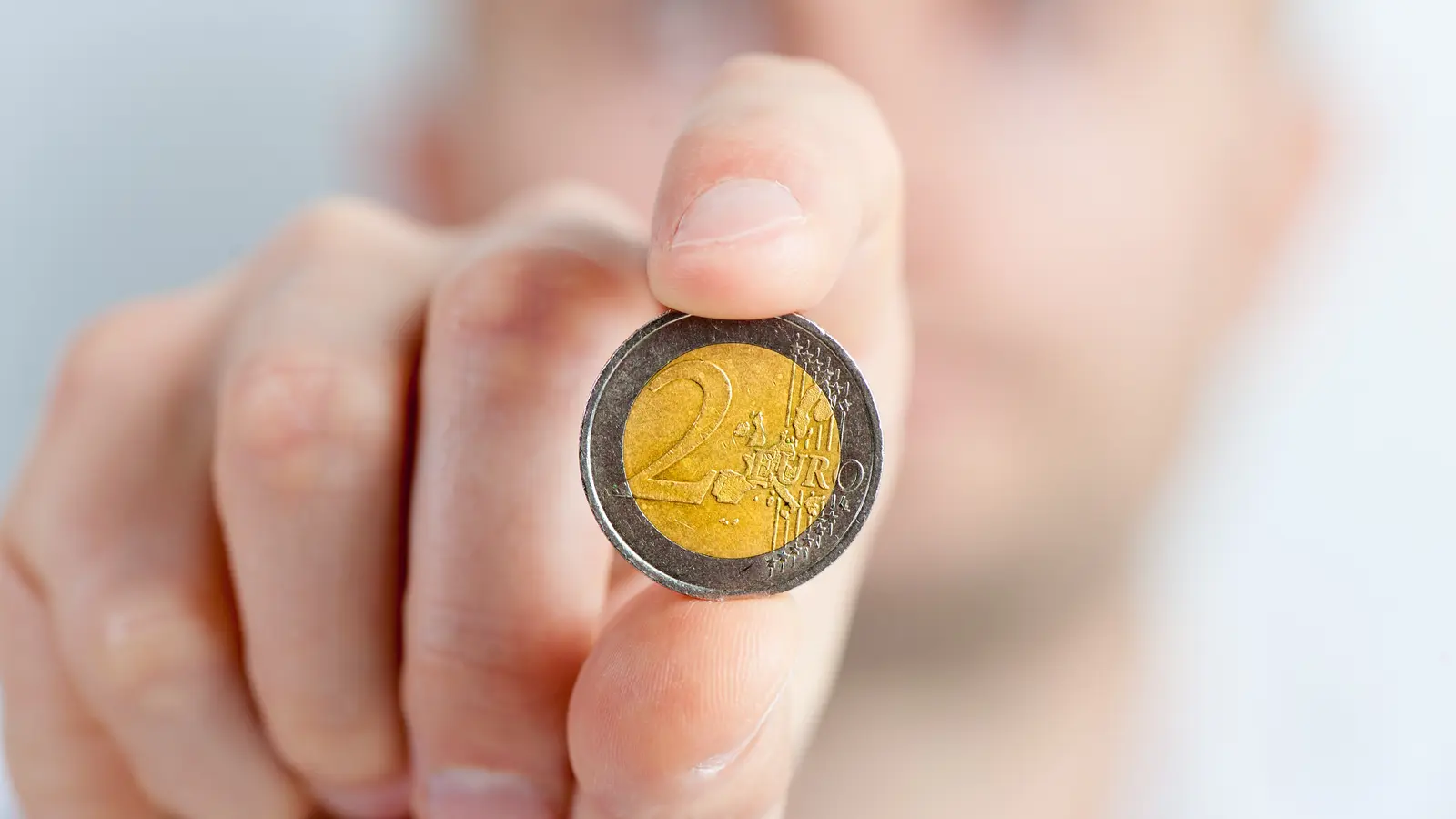 Main tenant une pièce de deux euros
