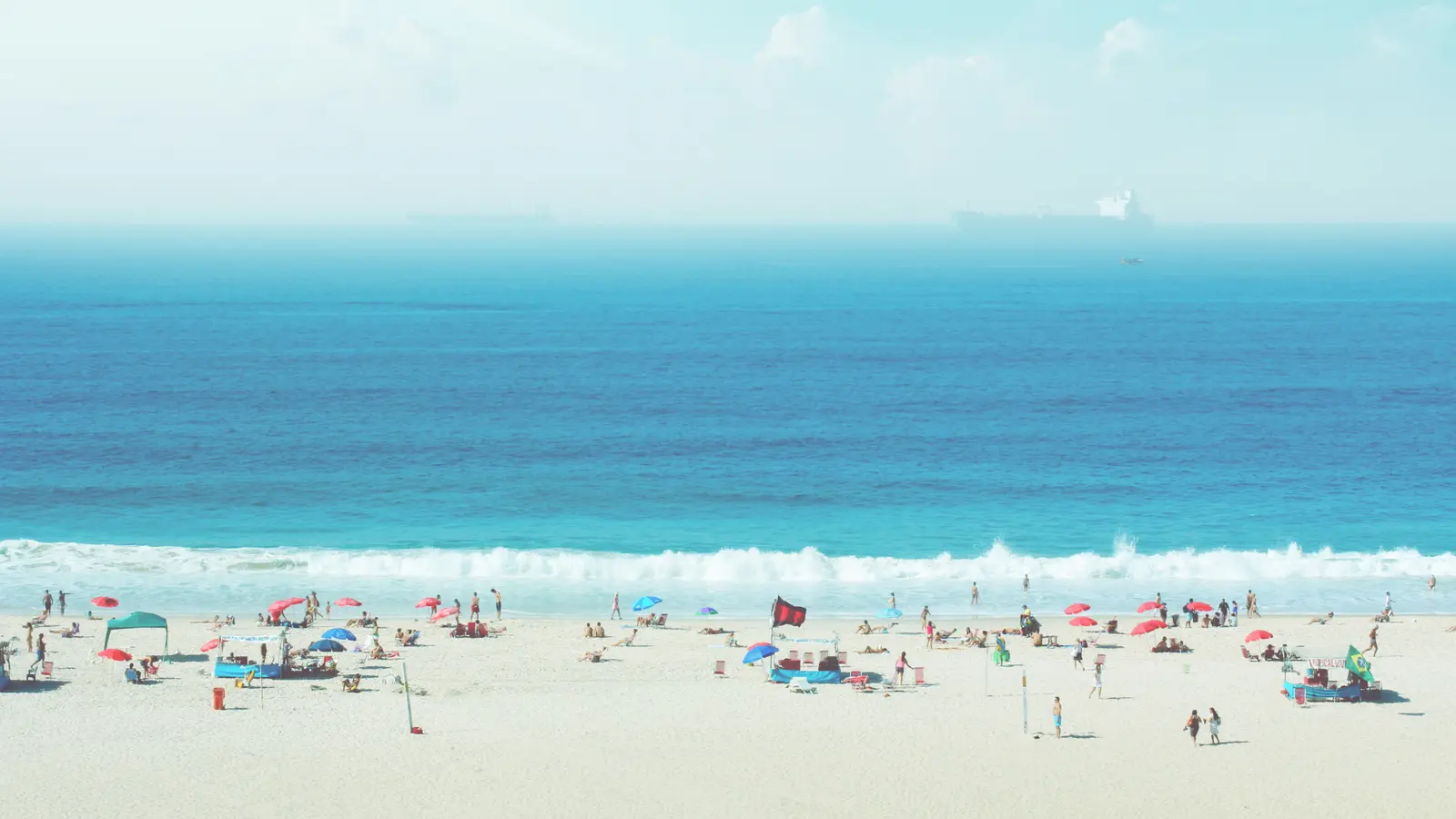 Plage de sable fréquentée au bord d'une mer turquoise