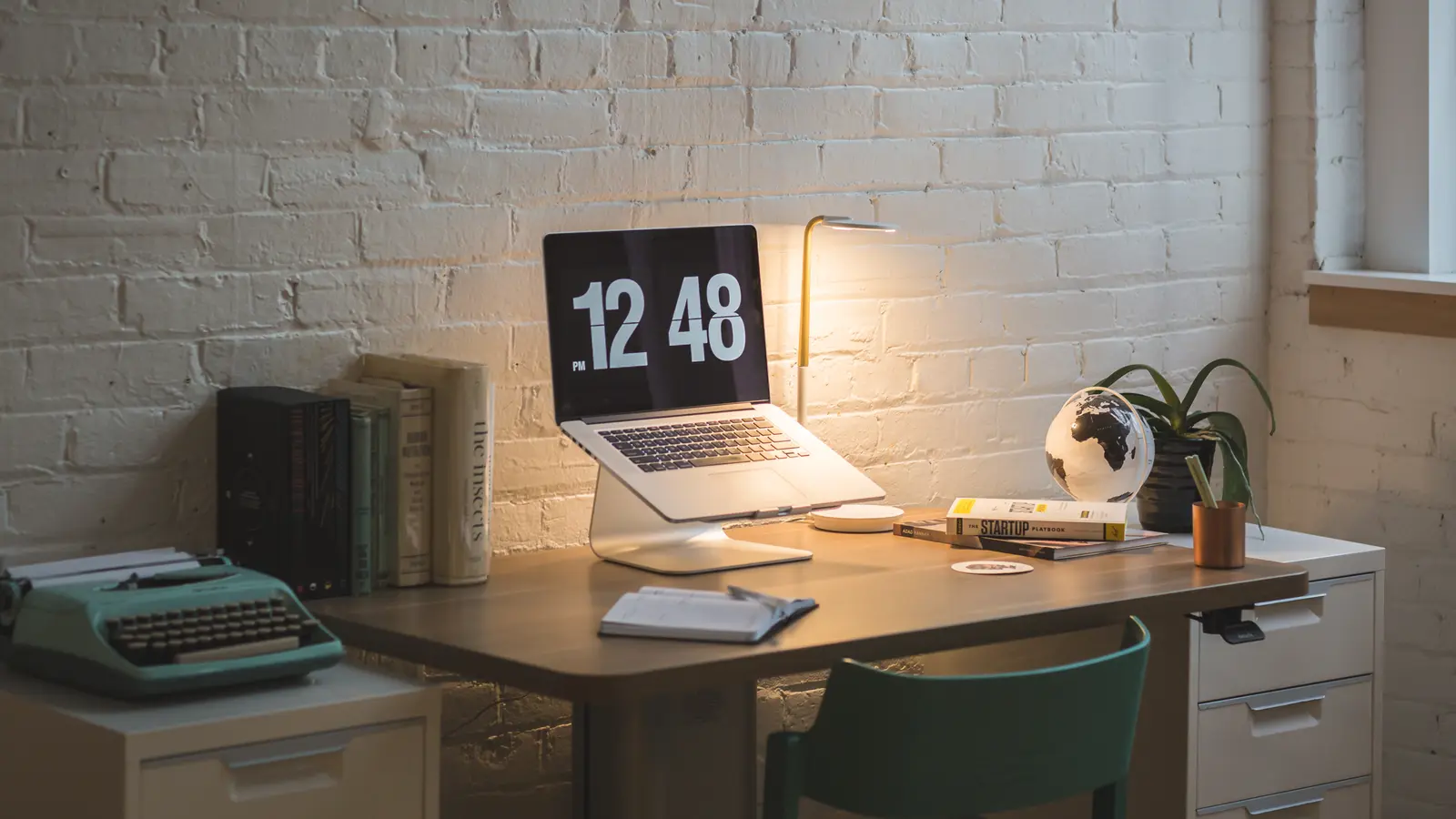 Bureau avec ordinateur portable, livres, machine à écrire et caissons de rangement