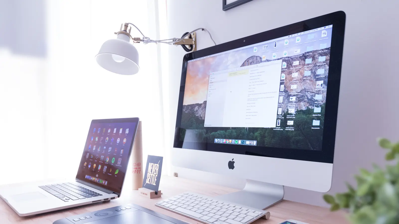 Ordinateur de bureau et ordinateur portable sur un bureau blanc éclairé par une lampe
