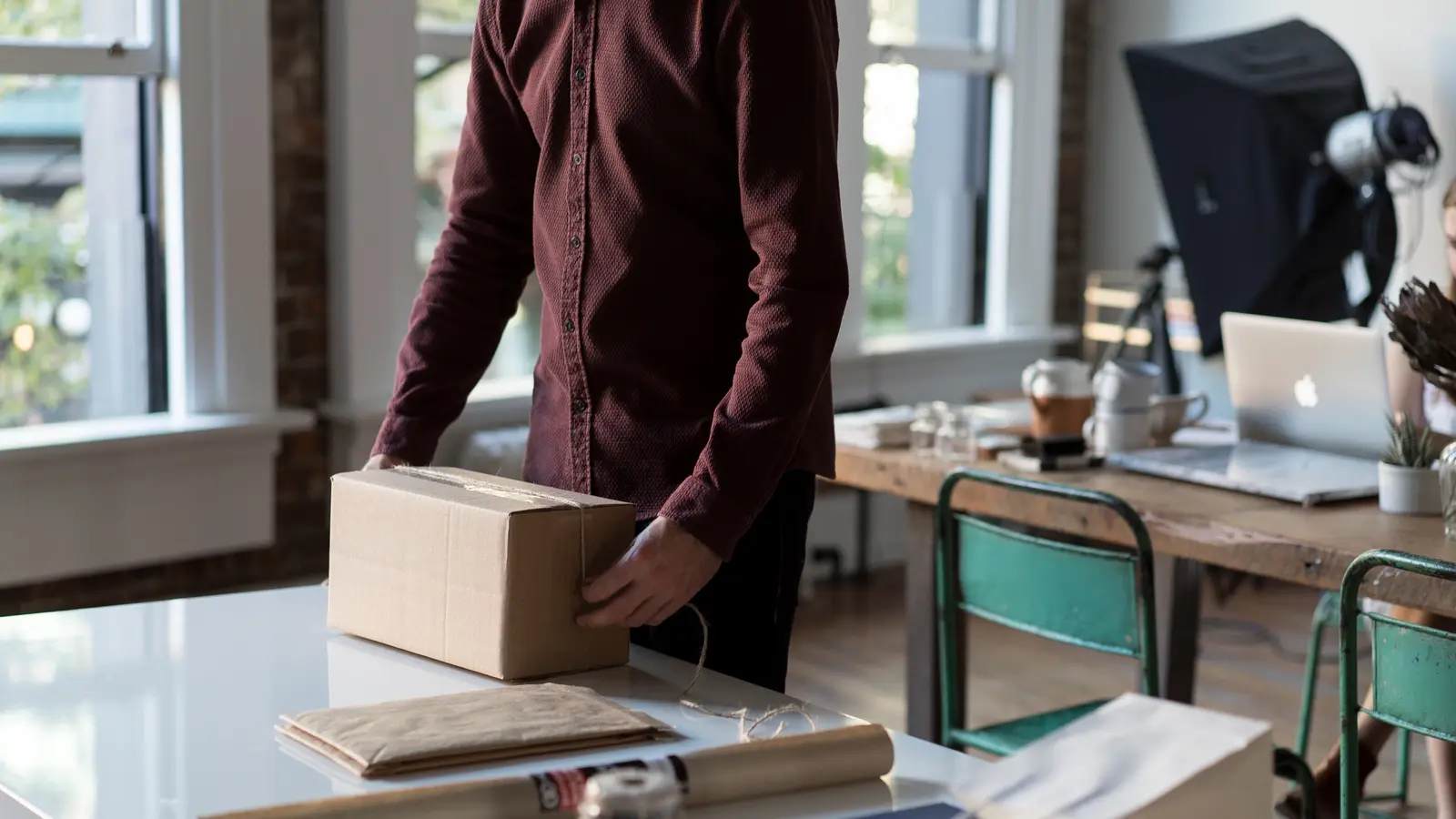 Homme emballant un carton sur une table dans un atelier