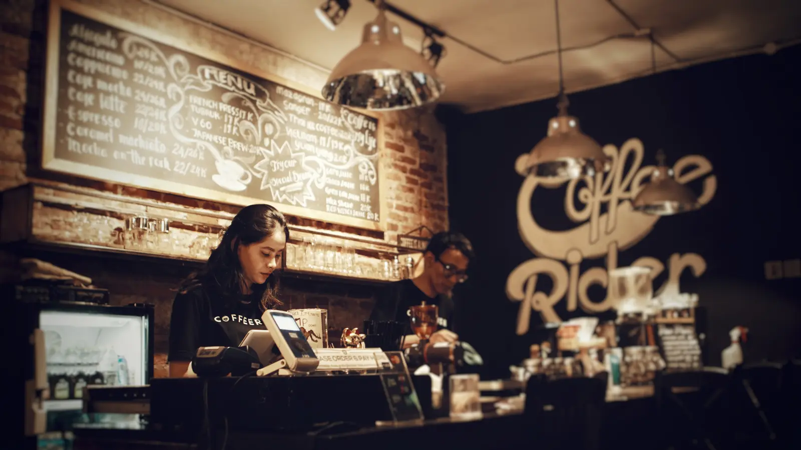 Serveurs derrière le comptoir d'un coffee shop, devant une caisse