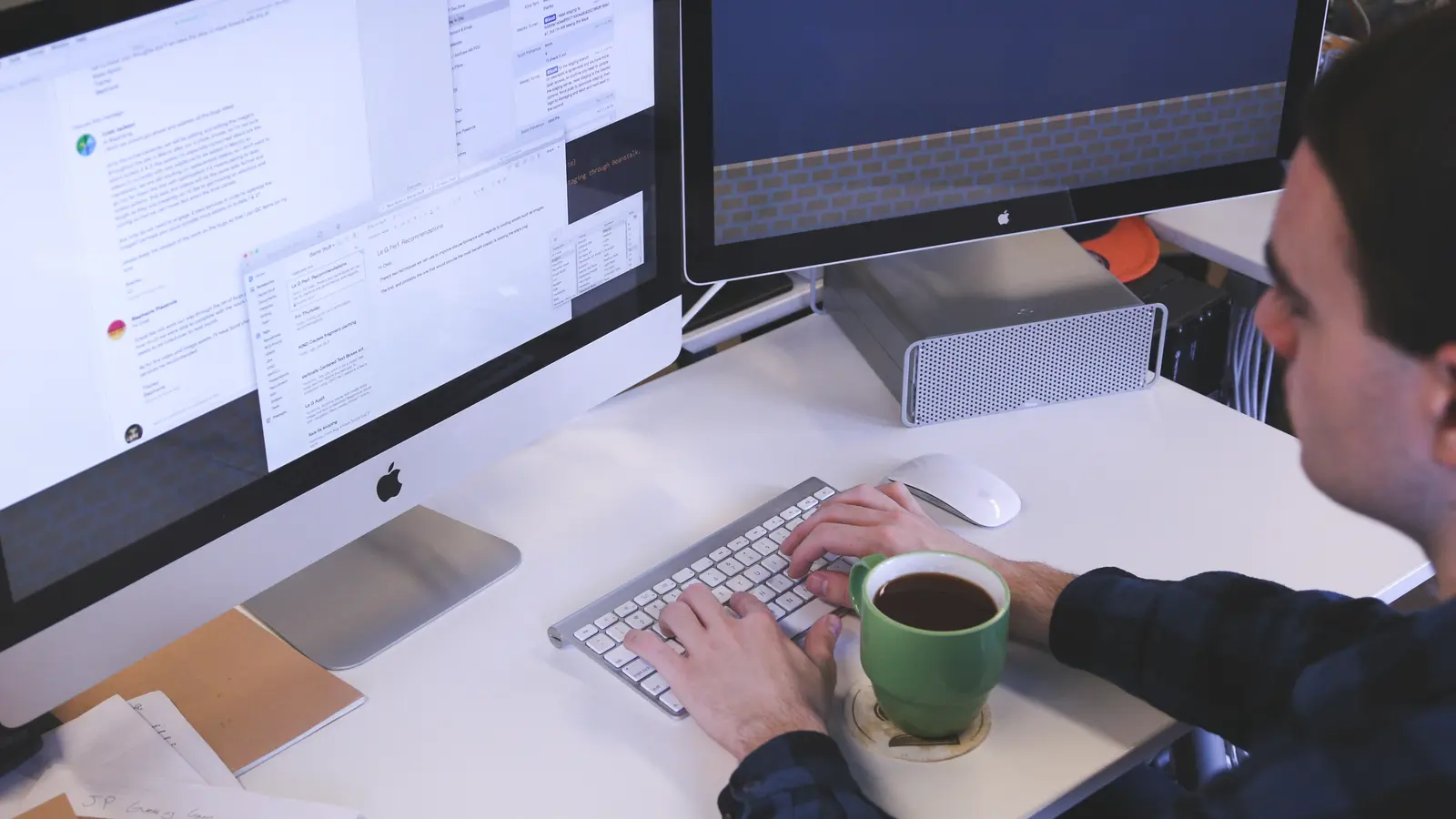 Homme tapant sur un clavier devant deux écrans d'ordinateur, une tasse à la main