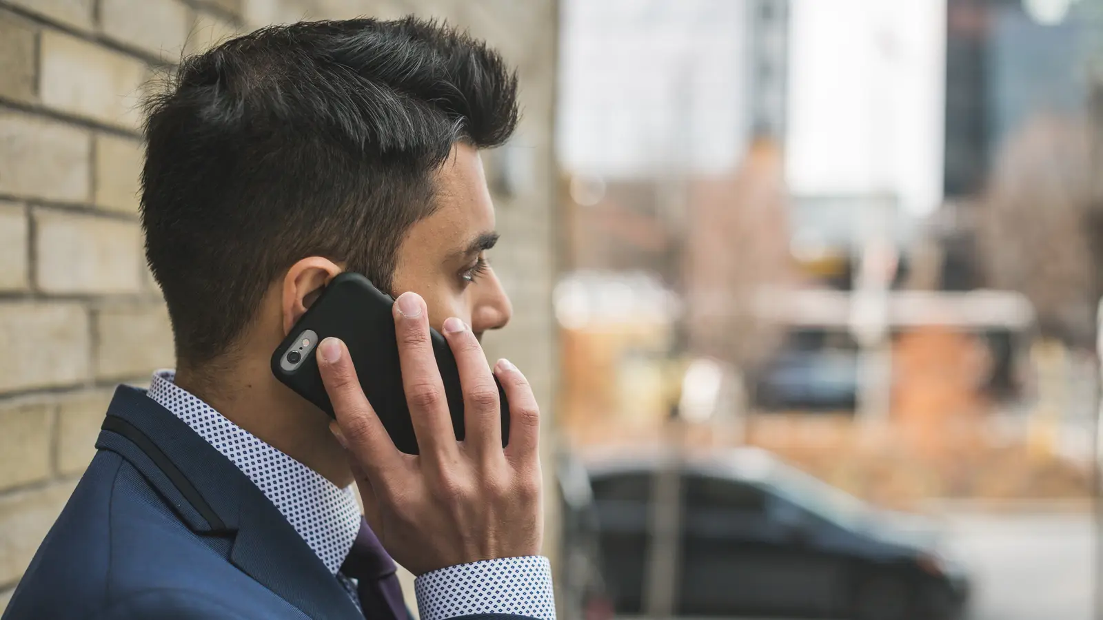 Homme en costume au téléphone devant une fenêtre