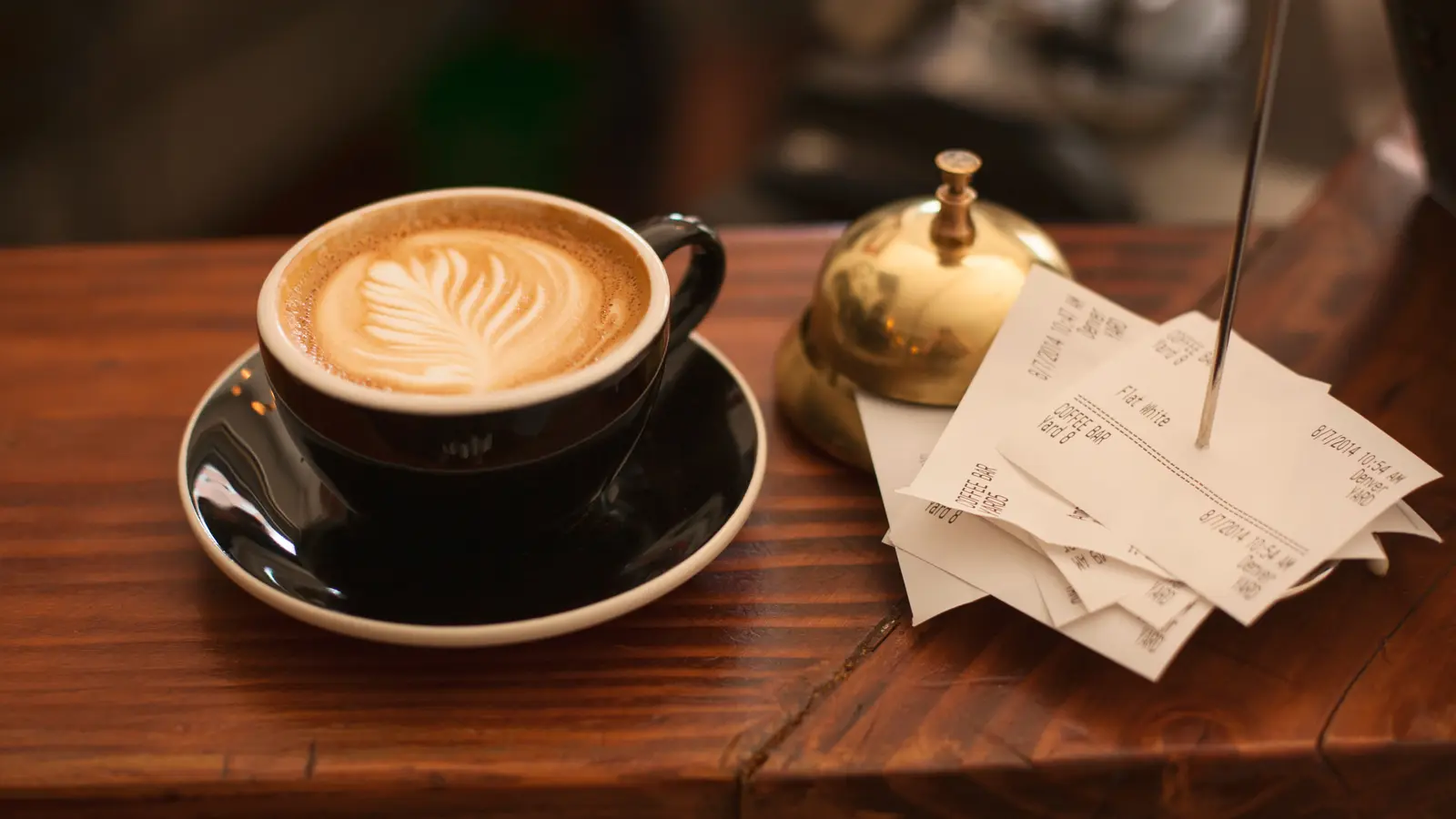 Tasse de café latte à côté d'une sonnette et de tickets de caisse piqués sur une pointe